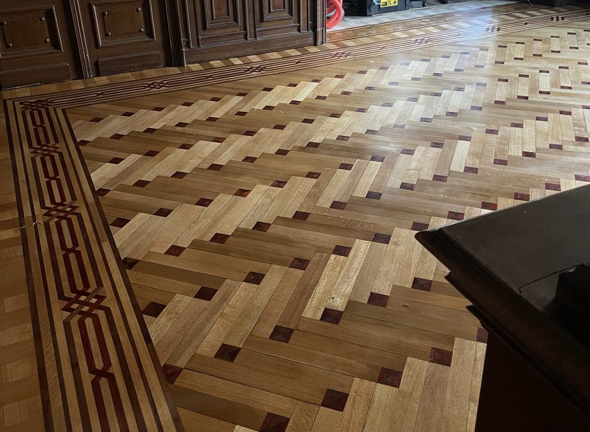 Parquet ancien à motif tressé, bordé d'une frise marquetée à filets rouges