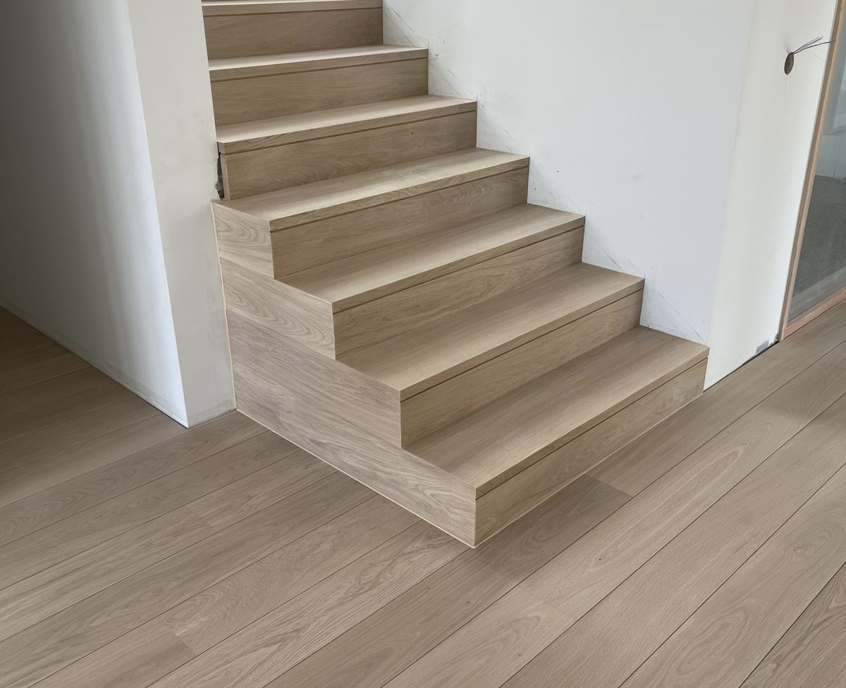 Escalier habillé en chêne clair, marches et contremarches, dans le prolongement du parquet